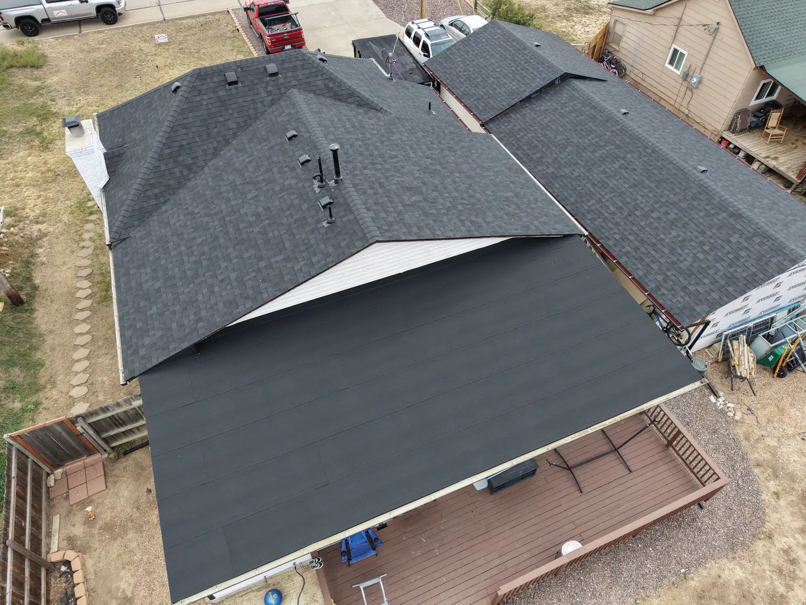 Finished charcoal shingle roof tied into a low-slope patio roof over a back deck