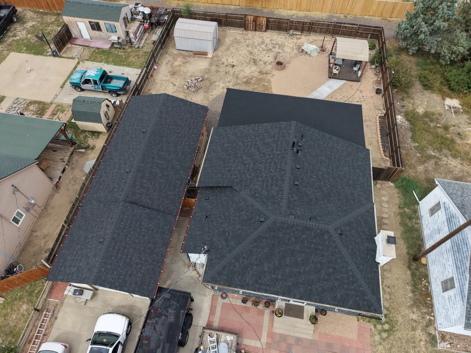 Drone view of a finished charcoal shingle roof with a low-slope section at the back