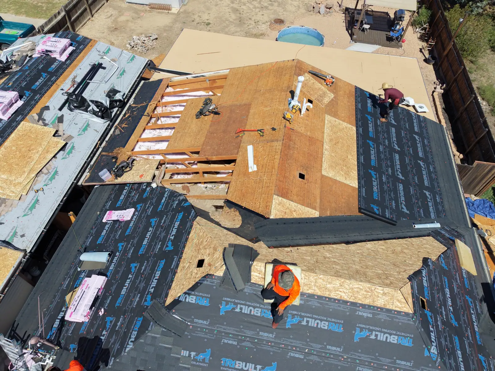 New sheathing patched into an old plank roof deck, synthetic underlayment going down on the slopes around it
