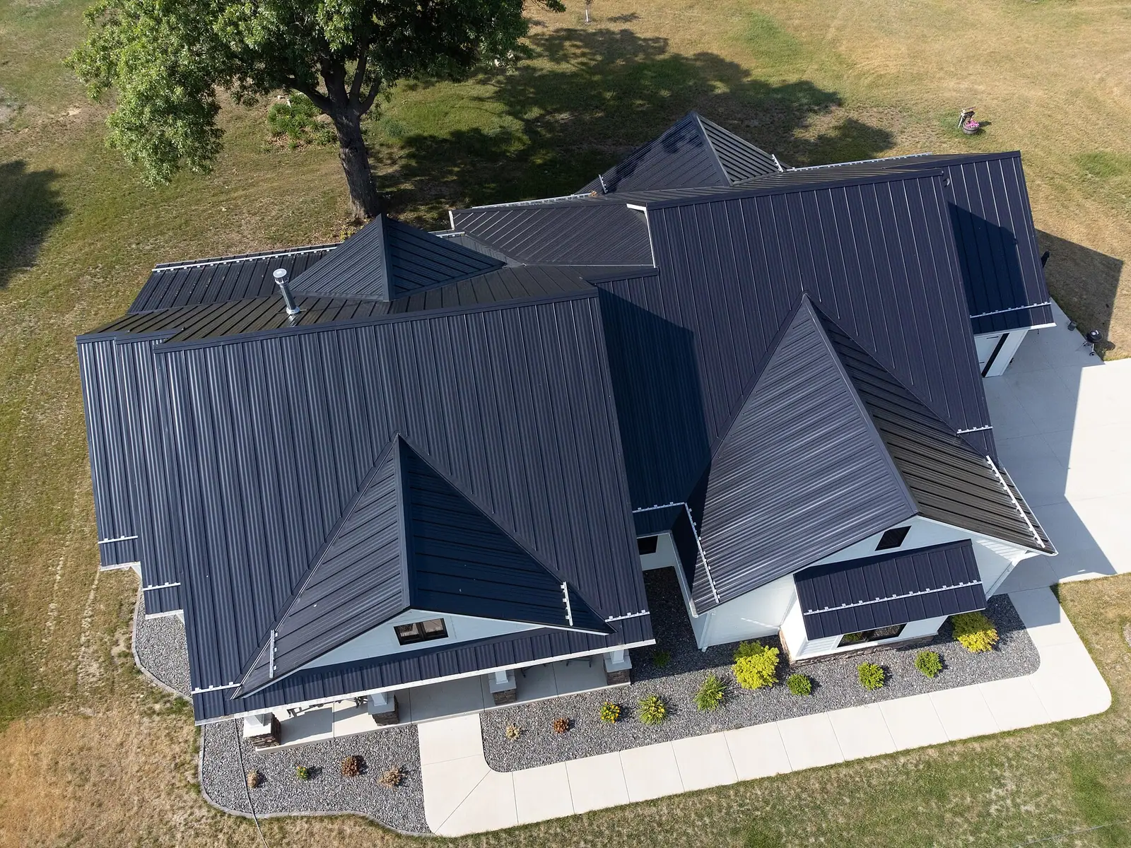 Aerial view of a dark standing seam metal roof with several gables and hips (stock photo)